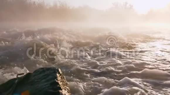在日出的时候在热带森林的中央泡沫状的河水从黑色的大岩石流下来令人惊奇的镜头视频的预览图