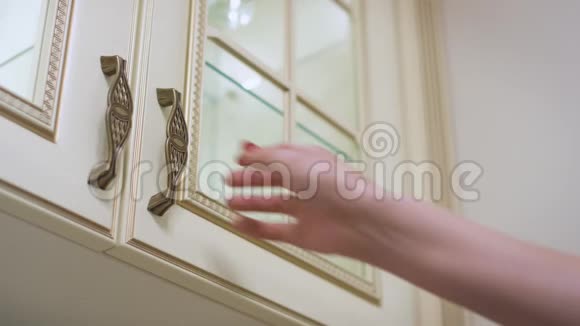 女人打开厨房的橱柜门在里面一个架子上拿着玻璃视频的预览图