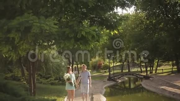 一对恩爱夫妻漫步在夏日公园女孩拿着一束洋甘菊视频的预览图