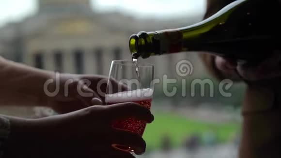 将粉红色香槟或起泡葡萄酒从瓶子中倒入玻璃杯中欧洲城市背景视频的预览图