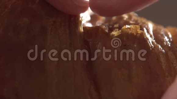 一个女孩的手特写打破了一个新鲜的牛角面包缓慢的运动新鲜甜点特写视频的预览图