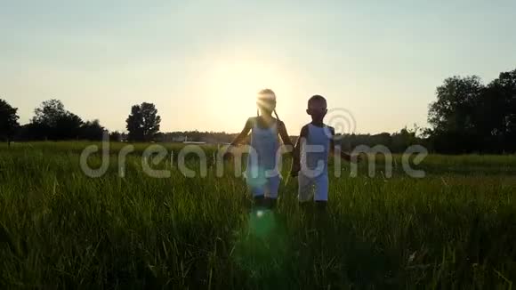 剪影儿童的身影男孩和女孩正在奔跑在太阳的背景下在日落时玩得很开心视频的预览图