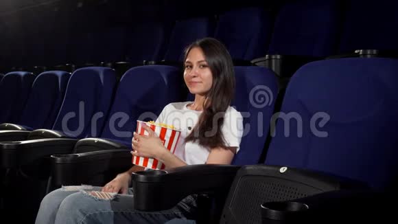 有魅力的年轻女子在电影院欣赏电影视频的预览图