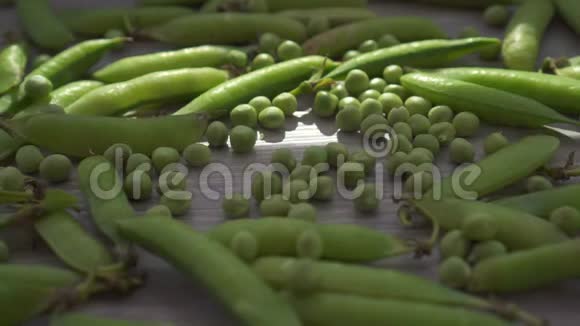 新鲜的青豆和豆荚特写在被太阳照亮的桌子上视频的预览图