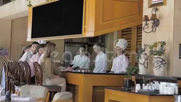 厨师们在餐厅的开放式厨房的酒吧桌上为顾客做白色制服的厨师视频的预览图