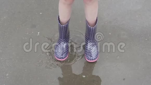 穿雨靴的孩子走进水坑视频的预览图