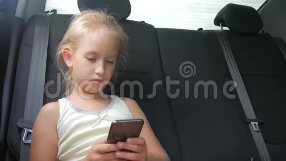 年轻迷人的金发女孩坐在车里用智能手机视频的预览图