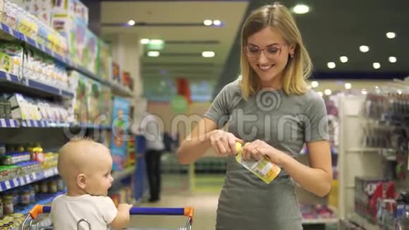 年轻迷人的女人和可爱的女儿在购物车选择产品的部分为儿童在超市这就是视频的预览图