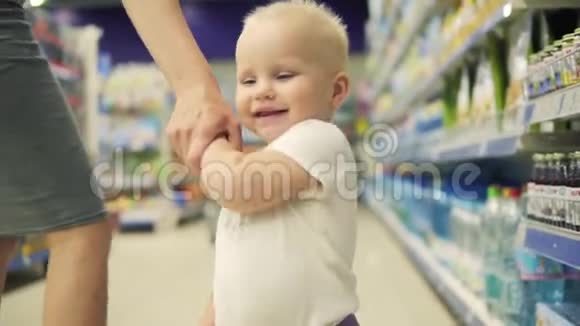 年轻漂亮的妈妈和她可爱的宝贝一起在超市购物牵着手走到视频的预览图