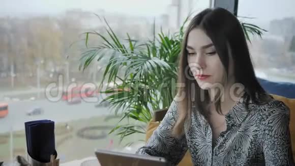 年轻女子在平板电脑上打字聊天写博客自由职业者在咖啡馆工作现代同事成功人士视频的预览图