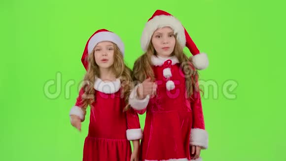 戴着红色圣诞帽的孩子们送空气亲吻绿色屏幕慢动作视频的预览图