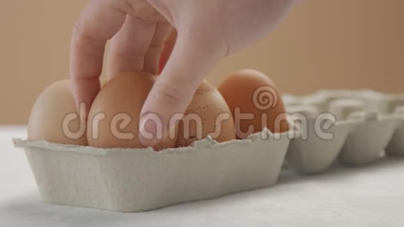 女人手把一个棕色的鸡蛋放在盒子里关上它视频的预览图