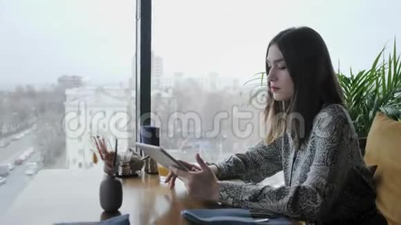 年轻女子在平板电脑上打字聊天写博客自由职业者在咖啡馆工作现代同事成功人士视频的预览图