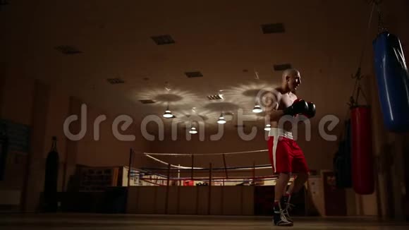 一个穿着拳击鞋和短裤的男人在体育馆里打拳击总体计划视频的预览图