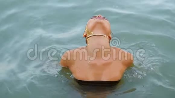 海滩上水中迷人的女人从水中抬起头看着镜头调情视频的预览图