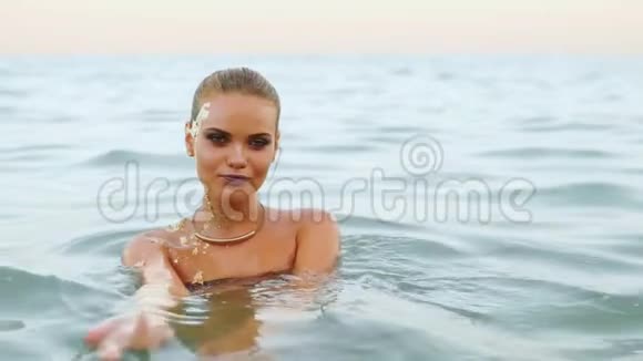 海滩上水中迷人的女人向她招手跟着她看着镜头和她调情视频的预览图