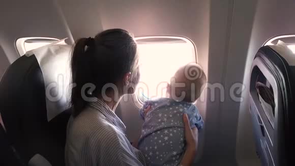 妈妈和她在飞机上的孩子看着窗外视频的预览图