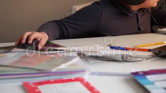 一个戴着大耳机的男孩忙于阅读和使用笔记本电脑视频的预览图