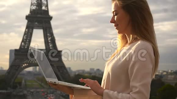 迷人的女人在埃菲尔铁塔附近用笔记本电脑慢动作聊天视频的预览图