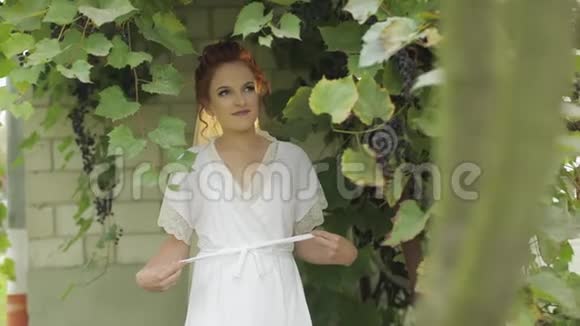 美丽可爱的新娘在花园里穿着睡衣和面纱婚礼早视频的预览图