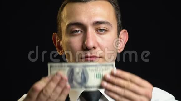 一个穿西装的人用一百元钞票把眼睛粘住视频的预览图