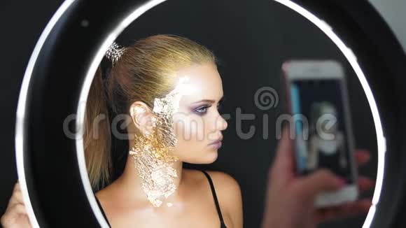 在镜子中看到一个美丽的长发模特有时尚的金色妆容覆盖着金色的金属碎片视频的预览图