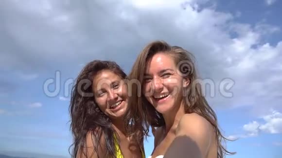 两个女人在海滩上用手机自拍微笑着旋转着享受大自然的假期视频的预览图