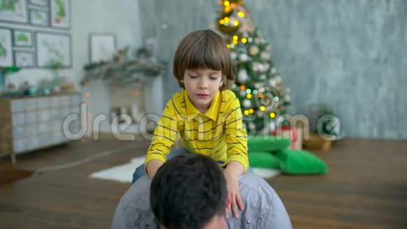 男人背着他非常可爱的儿子在家里快乐的父亲和小男孩在快乐的背景下玩得开心视频的预览图