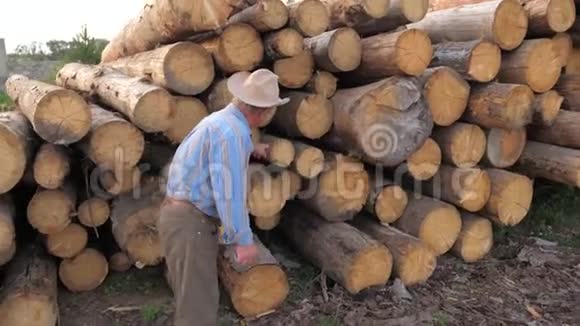 一个戴着帽子的商人沿着树木燃烧的原木走并检查它们视频的预览图