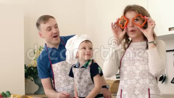 父母和儿子在厨房准备一份蔬菜和水果沙拉他们互相微笑玩耍视频的预览图