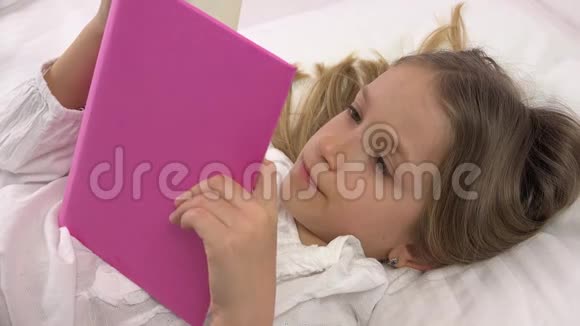 4K儿童在睡觉前放松阅读一本书女孩在床上休息肖像视频的预览图