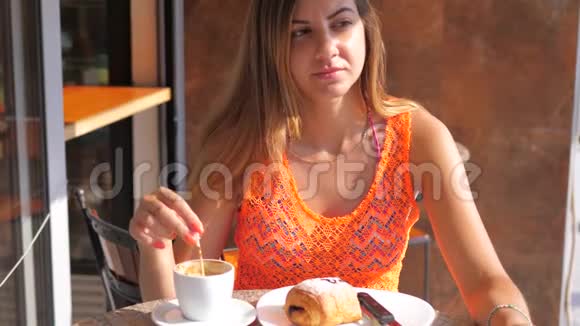年轻的布鲁内特女士在街上的咖啡馆里喝咖啡视频的预览图