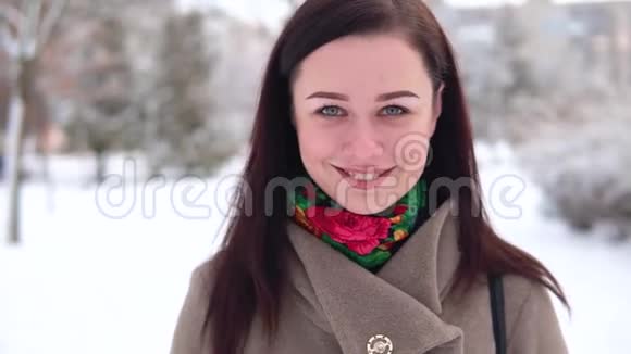 一个穿着外套的小女孩在冬天的公园里散步一边看着摄像机一边喝视频的预览图
