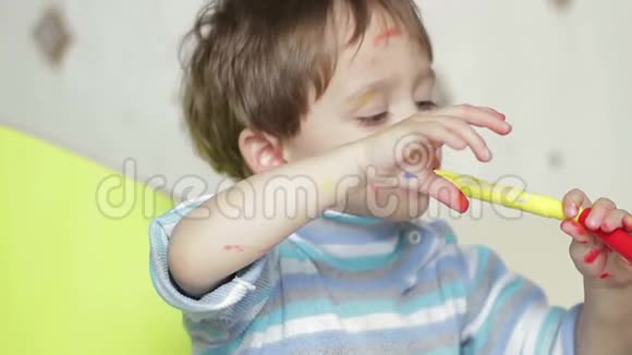 一张快乐的孩子的脸用毛笔画出来一个肮脏的孩子笑着玩耍这孩子被涂上了颜色视频的预览图