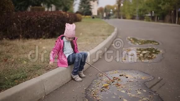 一个悲伤的小女孩独自在秋天的水坑里玩耍视频的预览图