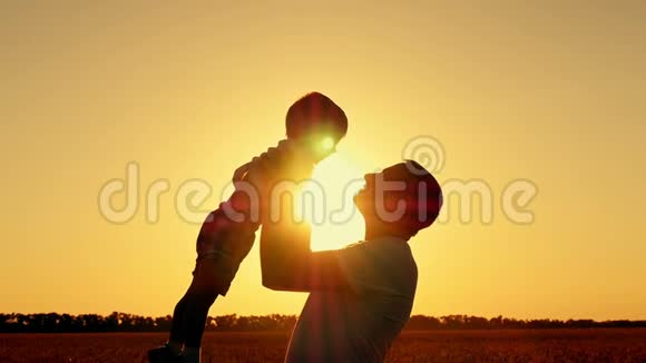 父亲和儿子在麦田里玩耍夕阳下一个幸福的家庭剪影视频的预览图