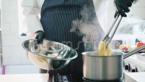 厨师在商业厨房用火钳取出一个沸腾的意大利面食视频的预览图