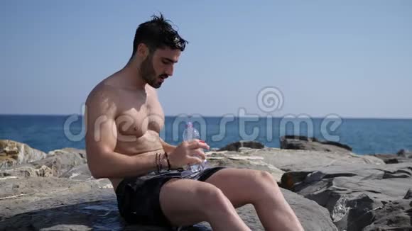 穿着漂亮衬衫的肌肉男用塑料瓶在胸前倒水视频的预览图