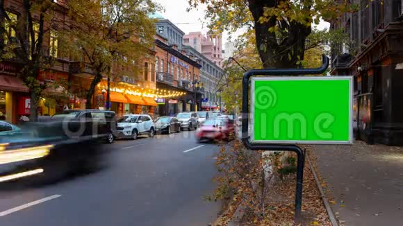 一个广告牌有一个绿色的屏幕背景是秋天的城市交通长时间曝光时间流逝视频的预览图