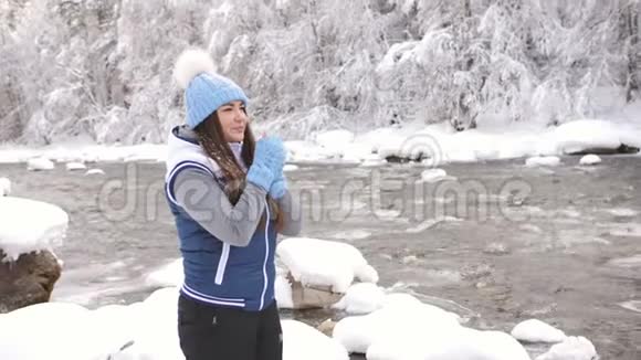 冬天森林里一条山河附近的美女画像女人揉着他的手呼吸着温暖视频的预览图