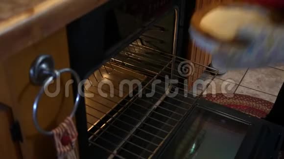 女人把饼皮放在乡村厨房的烤箱里视频的预览图