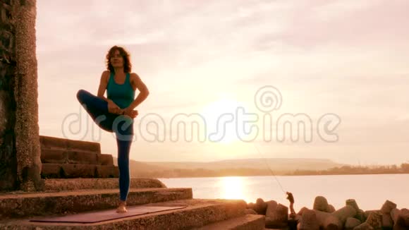 成人妇女在日落海滩上练习瑜伽视频的预览图