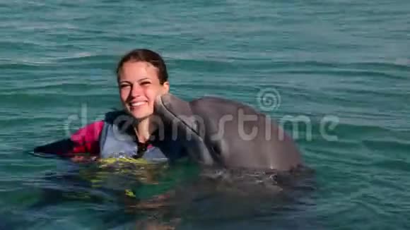 海豚在蓝色的水里亲吻年轻的女人微笑的女人和海豚一起游泳视频的预览图