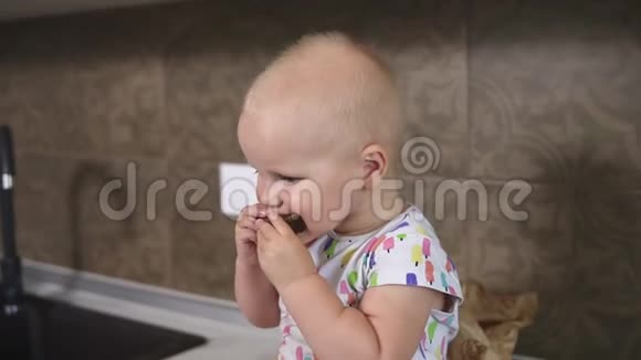 一个可爱的小宝宝吃一块面包小可爱的婴儿吃面包坐在厨房里慢镜头视频的预览图