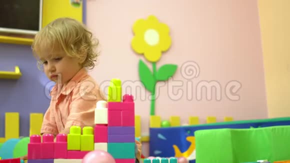 金发学龄前幼儿在幼儿园玩多色积木托儿所的儿童发展视频的预览图