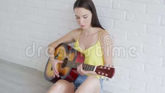 有魅力的女人在墙边弹吉他视频的预览图
