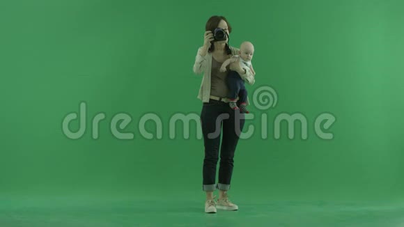一个年轻的女人带着她的孩子在绿色的屏幕上拍照视频的预览图