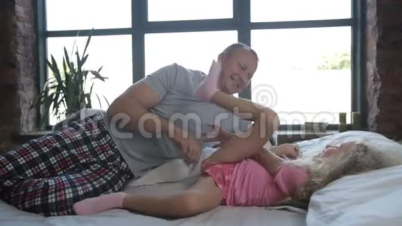 可爱的爸爸和可爱的女儿在床上玩耍视频的预览图