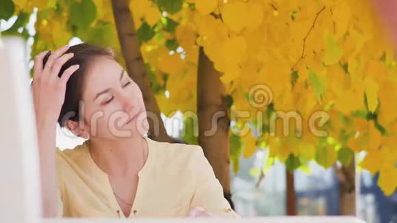 奇妙的秋景一位迷人的年轻女子坐在街头咖啡馆的桌子旁开心地笑着视频的预览图