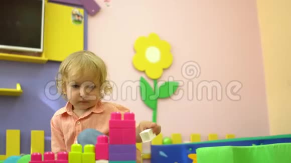 美丽的金发幼儿在幼儿园玩多种颜色的积木儿童发展视频的预览图